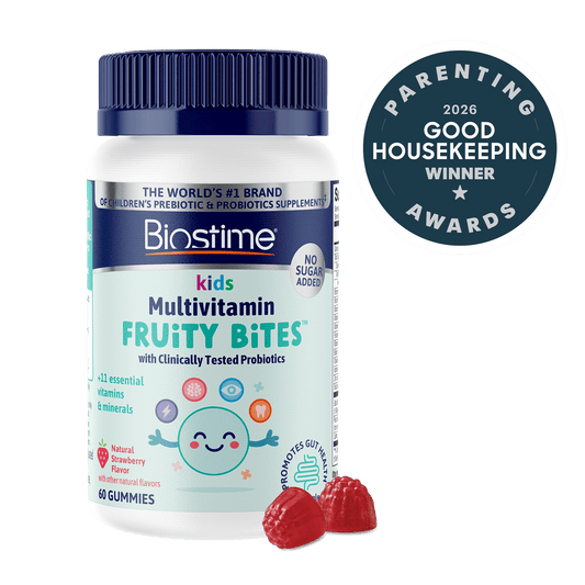 Biostime Kids Multivitamin Fruity Bites gummies bottle with a dark blue cap and white label, shown on a white background with a dark blue 2026 Good Housekeeping Awards badge and two raspberry gummies in front.
