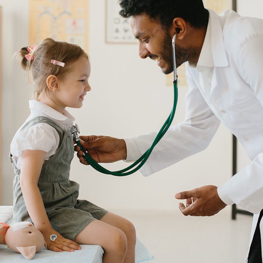 Doctor using a stethoscope on a young girl in a medical setting