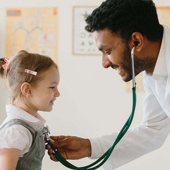 Doctor using a stethoscope on a young girl in a medical setting