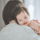 Baby being held by an adult with a blurred background
