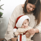 Woman and child wearing Santa hats with a gift, likely during Christmas.
